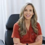 Dr. Marissa Gaucher, ND – Cosmetic Injector - Dr. Marissa Gaucher Dr. Marissa Gaucher, ND, seated in red scrubs at her clinic