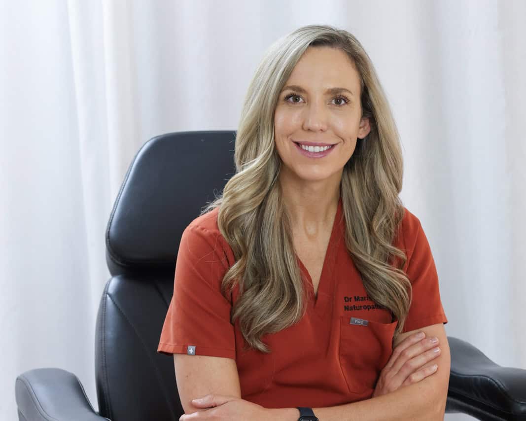 Dr. Marissa Gaucher, ND, seated in red scrubs at her clinic
