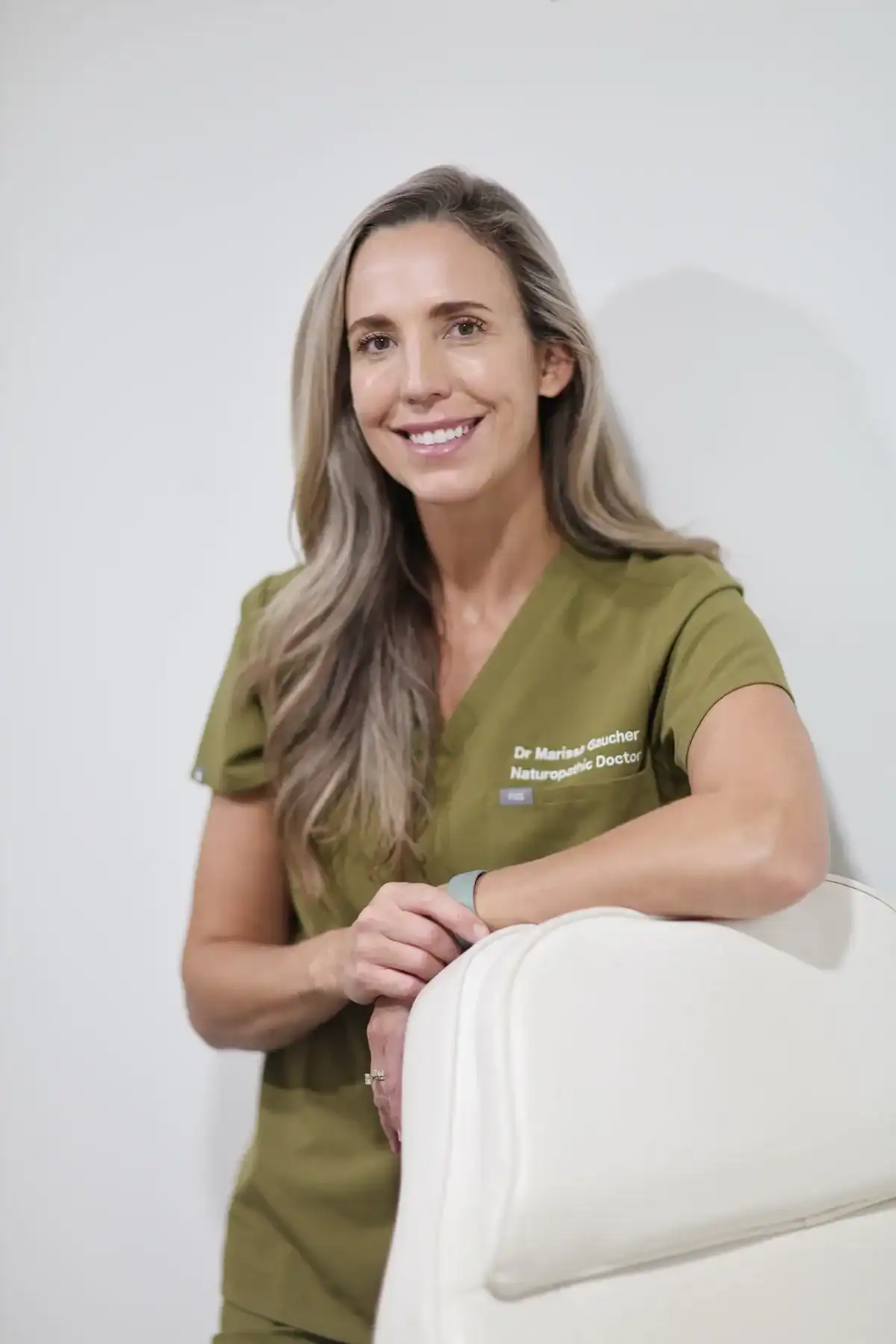 Dr. Marissa Gaucher in olive scrubs beside a white chair